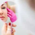 Woman looking in mirror being evaluated as a facelift candidate in Scottsdale, AZ