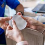 Doctors hands a woman a breast implant as he explains its type and benefits