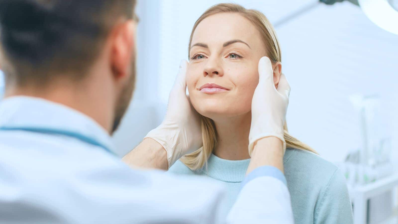 Woman smiling as her surgeon examines her face before facial fat grafting surgery