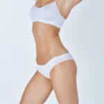 Woman with a slimmer waist and toned abdomen after weight loss and body contouring procedures.